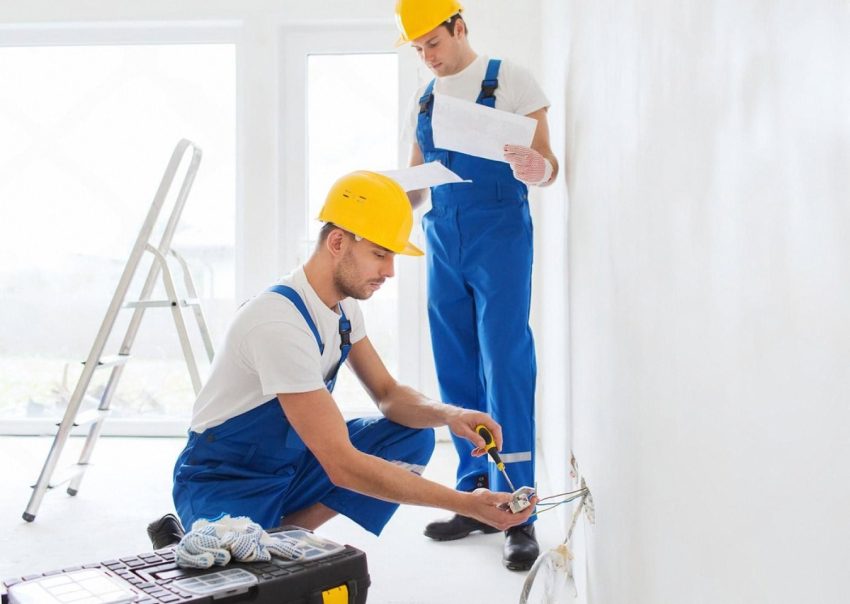 Two maintenance technicians inspecting electrical wiring in a new Dubai home