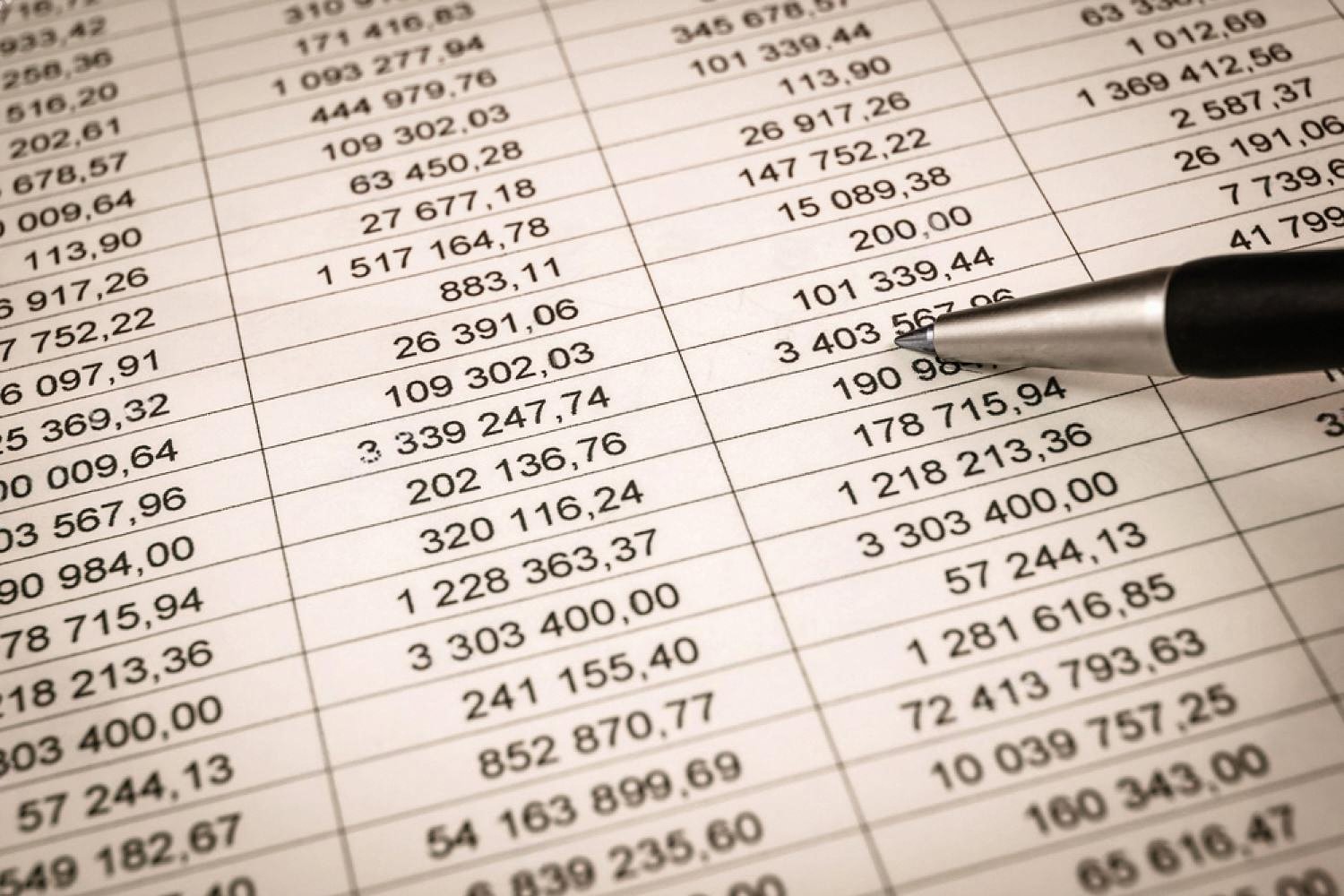 Close-up of a financial ledger with columns of figures being reviewed with a pen